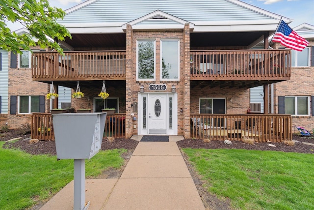 view of front of property featuring a balcony, brick siding, and a front lawn