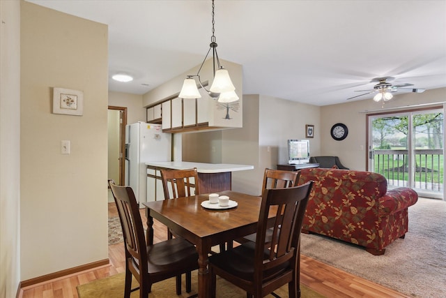 dining area featuring light wood-style flooring, a ceiling fan, and baseboards