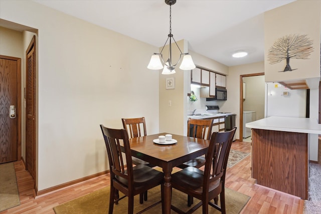 dining space featuring washer and dryer, light wood-type flooring, and baseboards