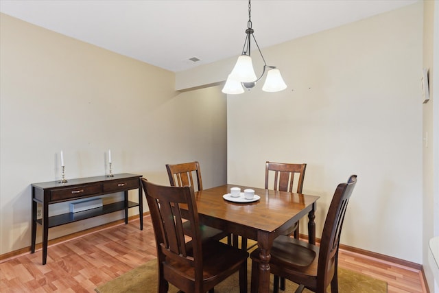 dining room featuring light wood-style floors, baseboards, and a chandelier
