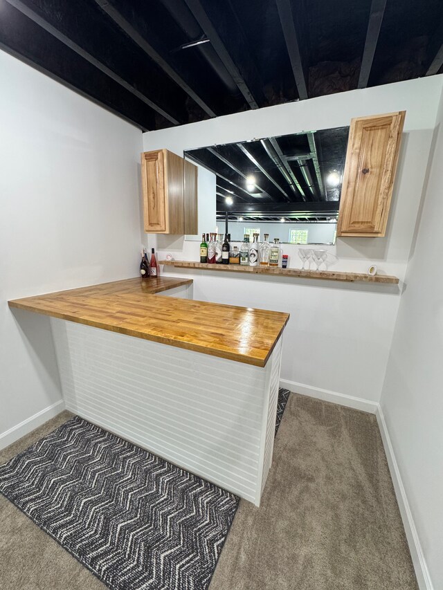 kitchen featuring carpet, butcher block countertops, a peninsula, and baseboards