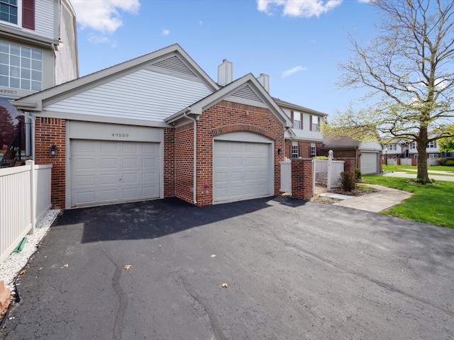 49559 Donovan Blvd, Plymouth, MI 48170 - view of front of house featuring brick siding, a chimney, driveway, a garage, and fence