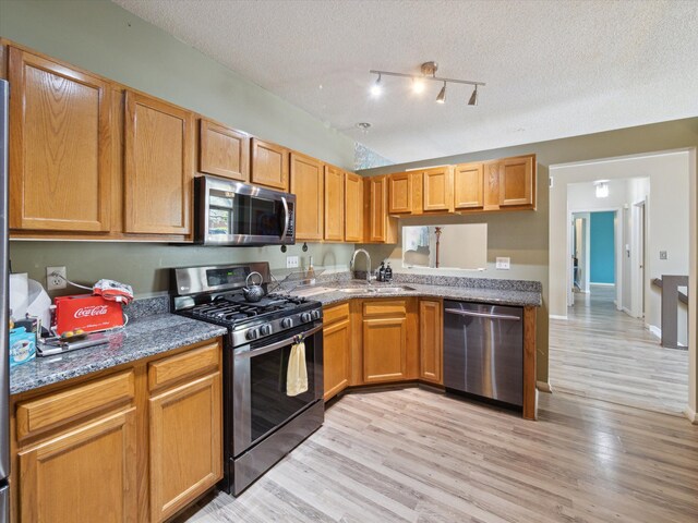 49559 Donovan Blvd, Plymouth, MI 48170 - kitchen with stainless steel appliances, a sink, a textured ceiling, stone countertops, and light wood-style flooring