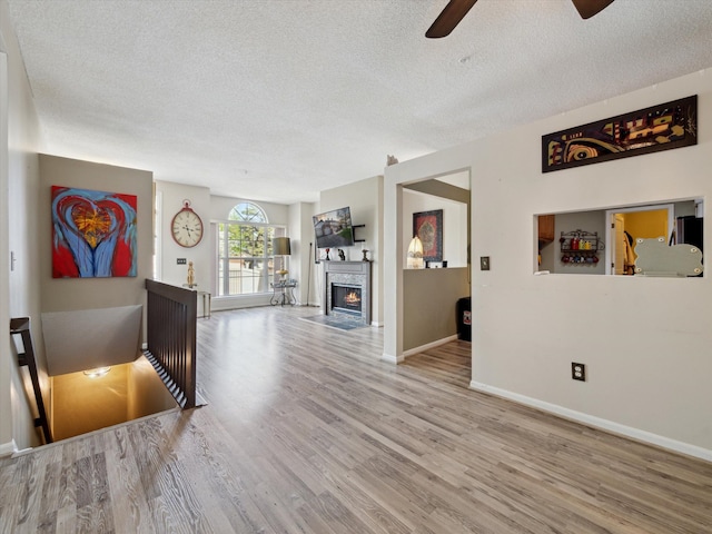 49559 Donovan Blvd, Plymouth, MI 48170 - living room with a textured ceiling, a ceiling fan, wood finished floors, baseboards, and a fireplace with flush hearth