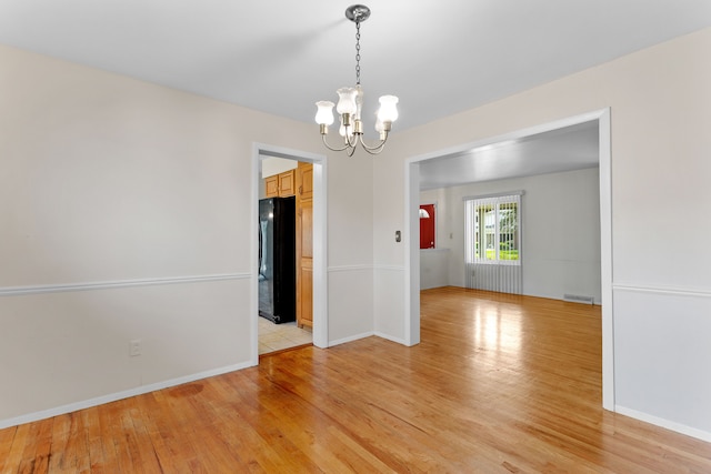 29458 Walker Dr, Warren, MI 48092 - spare room with a chandelier, light wood-style floors, and baseboards