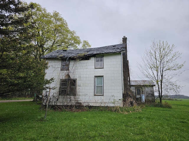 7697 Hogan Rd, Muir, MI 48860 - rear view of house featuring a lawn and a chimney