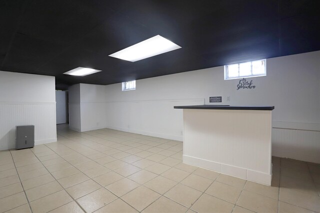 basement featuring a wainscoted wall and light tile patterned floors