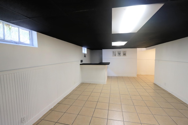 basement with light tile patterned floors and wainscoting