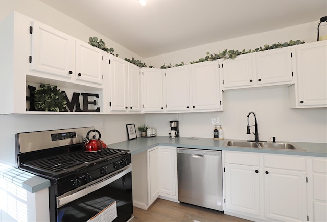 kitchen featuring appliances with stainless steel finishes, a sink, white cabinetry, and light wood-type flooring