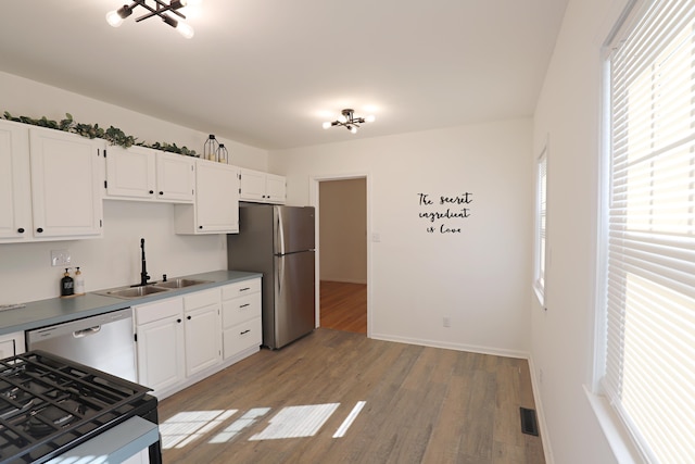 kitchen featuring stainless steel appliances, a sink, healthy amount of natural light, and light wood-style floors