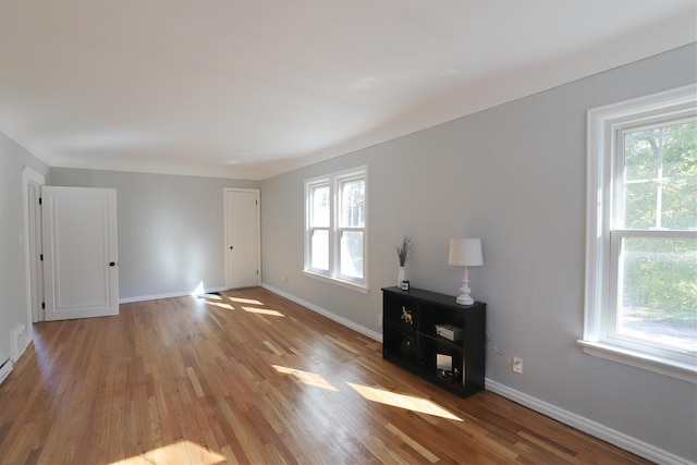 unfurnished living room with plenty of natural light, wood finished floors, and baseboards
