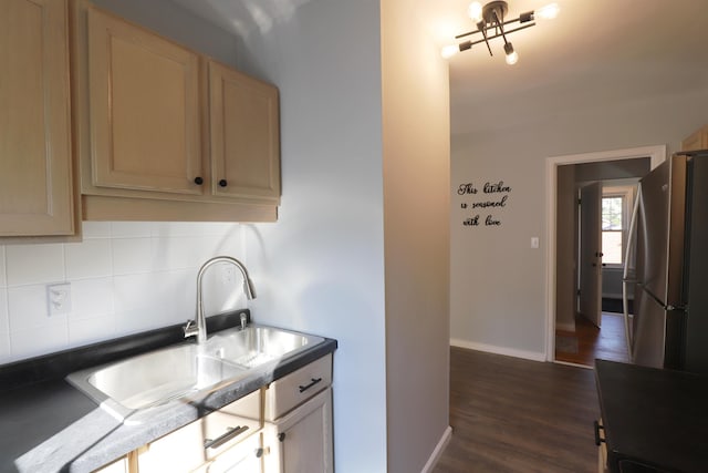 kitchen with freestanding refrigerator, backsplash, a sink, dark wood-type flooring, and baseboards