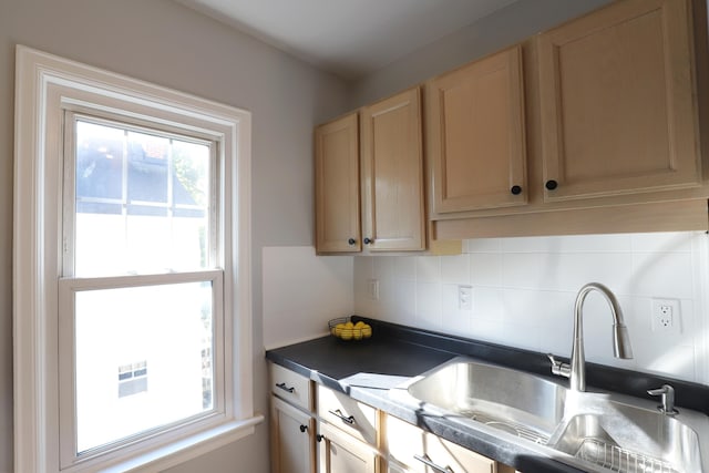kitchen featuring a sink, plenty of natural light, tasteful backsplash, and dark countertops