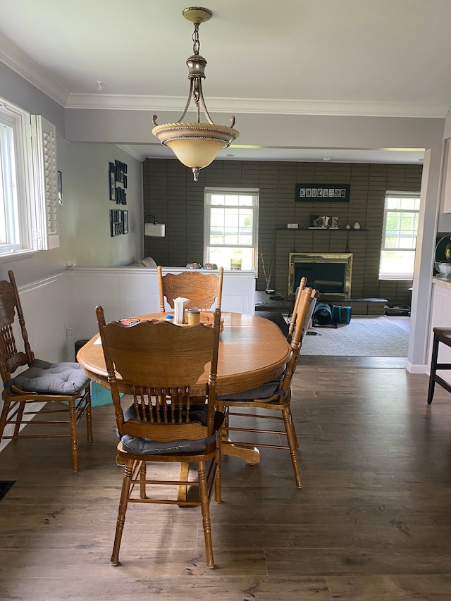 dining area with ornamental molding, wood finished floors, plenty of natural light, and a fireplace