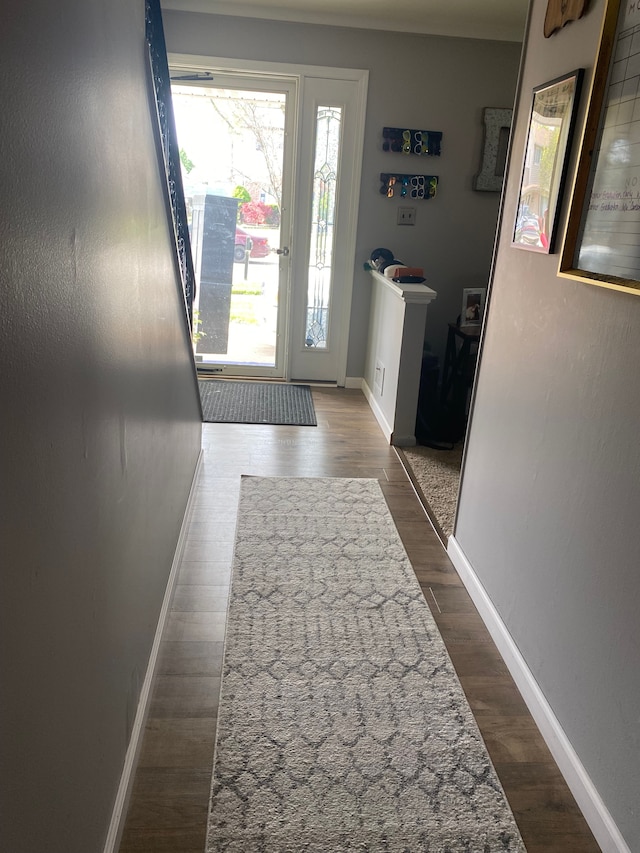 doorway to outside featuring baseboards and dark wood finished floors