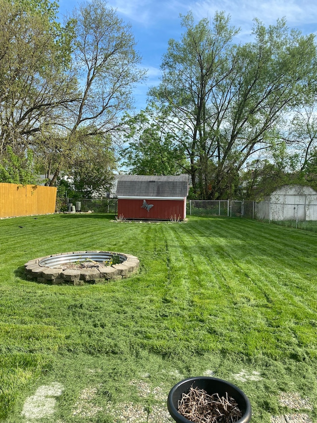 view of yard with a storage unit, an outbuilding, and a fire pit