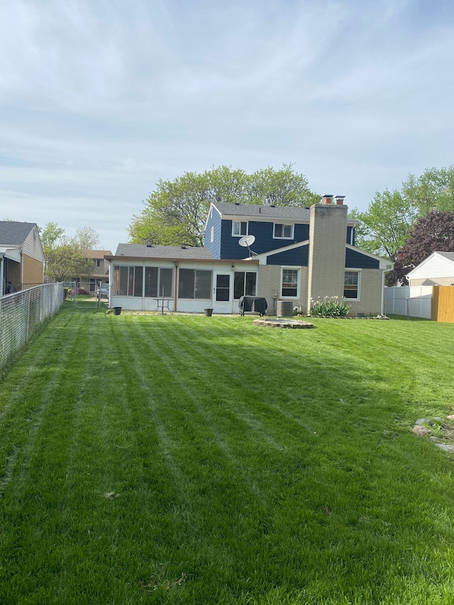 rear view of property featuring a sunroom and a chimney