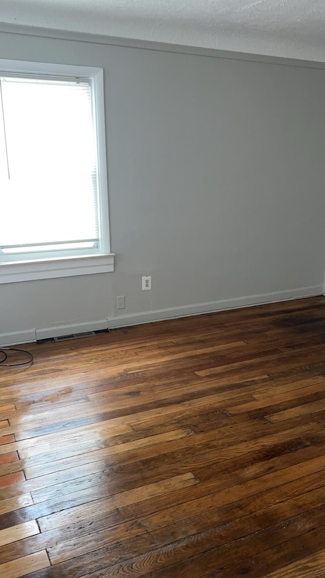 empty room with dark wood-type flooring and baseboards
