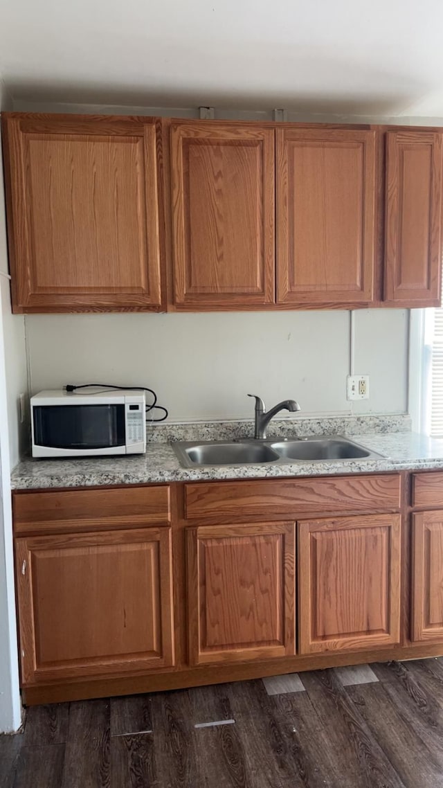kitchen with white microwave, a sink, dark wood-style floors, and brown cabinets