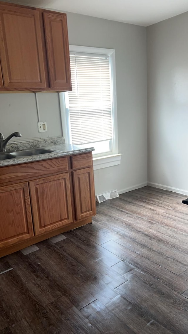 kitchen featuring a sink, dark wood-type flooring, brown cabinetry, and light countertops