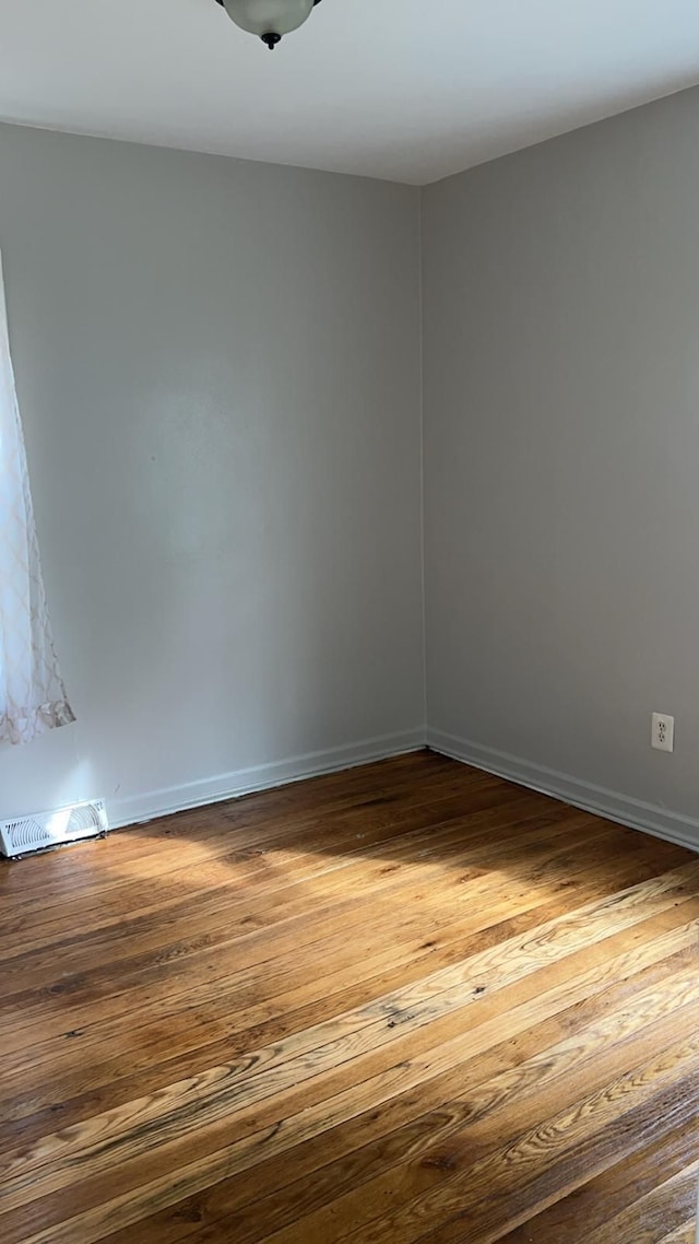 empty room featuring hardwood / wood-style flooring and baseboards