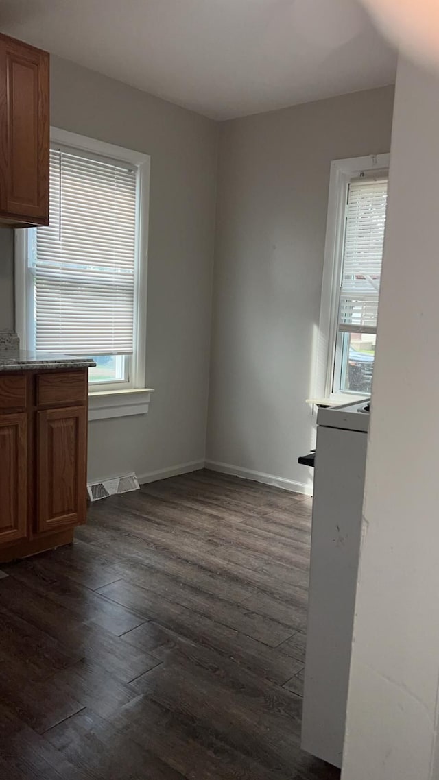 unfurnished dining area with dark wood-style floors and baseboards