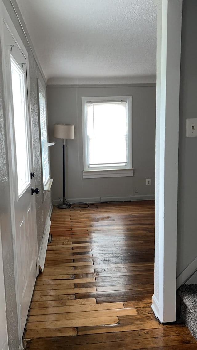 unfurnished living room featuring plenty of natural light, hardwood / wood-style flooring, and baseboards