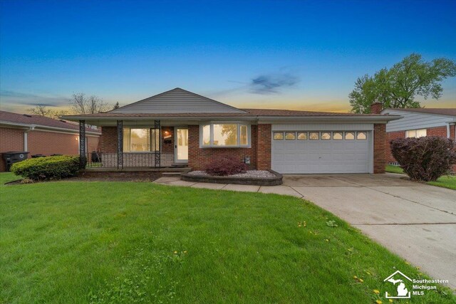 ranch-style house featuring an attached garage, covered porch, concrete driveway, a front lawn, and brick siding