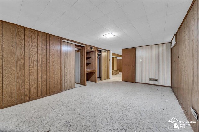 finished basement with wooden walls and tile patterned floors