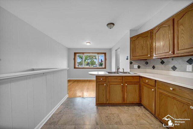 kitchen with brown cabinets, a sink, light countertops, and baseboards