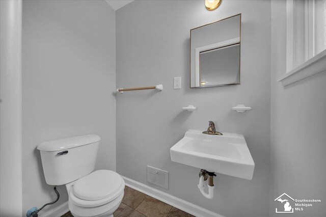 bathroom featuring toilet, baseboards, tile patterned flooring, and a sink