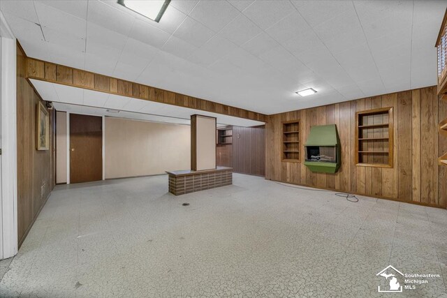 finished basement with wooden walls, built in shelves, and baseboards