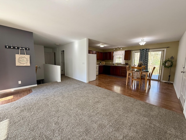 carpeted dining area with baseboards, wood finished floors, and a sink