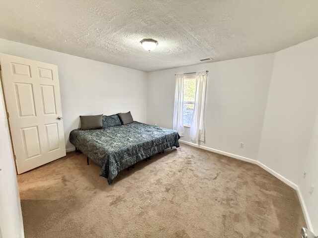 bedroom featuring carpet floors, baseboards, and a textured ceiling