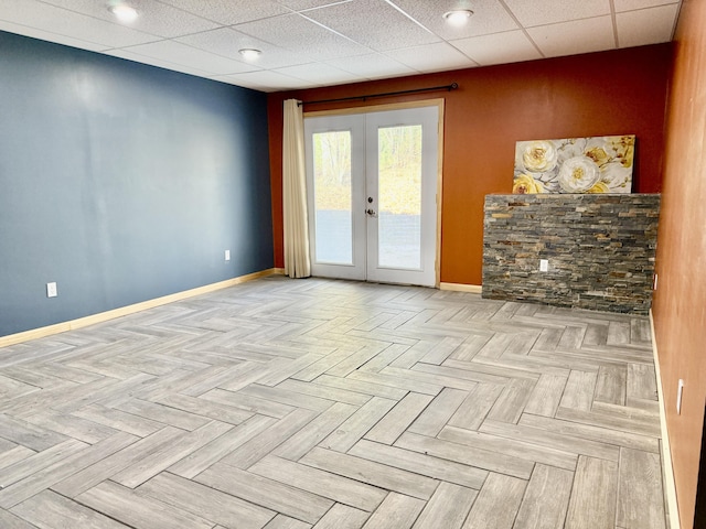 unfurnished room featuring french doors, baseboards, and a drop ceiling
