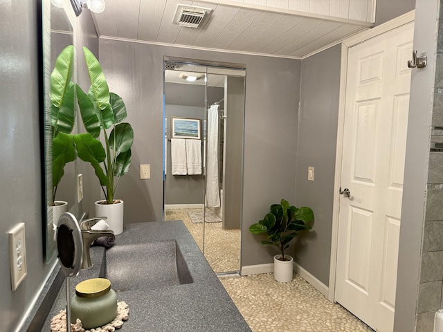 hallway with ornamental molding, baseboards, and wooden ceiling