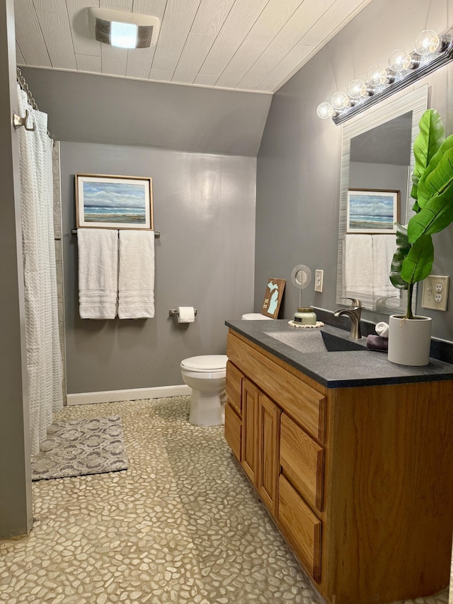 bathroom featuring vaulted ceiling, toilet, vanity, baseboards, and a shower with shower curtain
