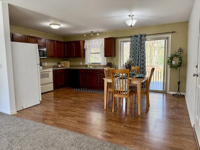 kitchen with white appliances, a sink, dark wood-type flooring, and baseboards