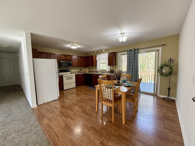 dining space featuring wood finished floors, baseboards, and track lighting