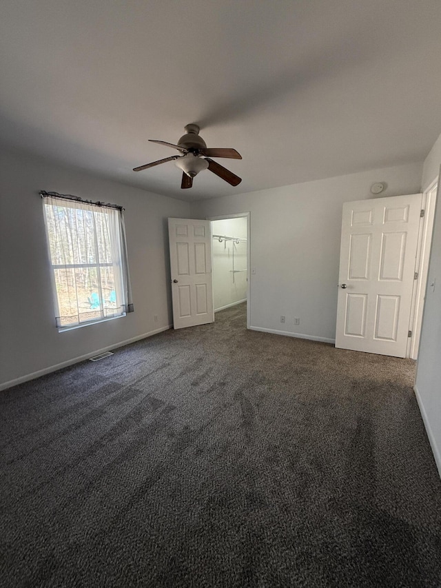 unfurnished bedroom featuring dark colored carpet, baseboards, and ceiling fan