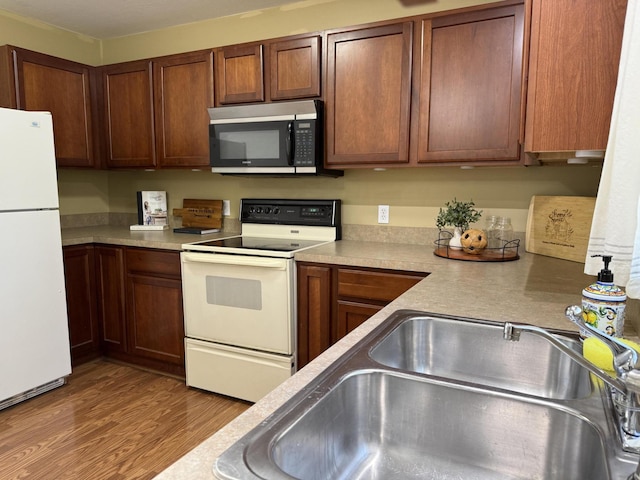 2184 Sugaridge Dr, Muskegon, MI 49445 - kitchen featuring white appliances, wood finished floors, light countertops, and a sink
