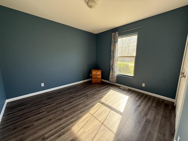 empty room featuring dark wood finished floors and baseboards