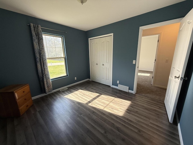 unfurnished bedroom featuring dark wood-type flooring, baseboards, and a closet