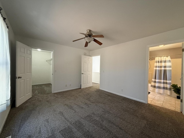 unfurnished bedroom featuring carpet flooring, baseboards, a spacious closet, and a ceiling fan