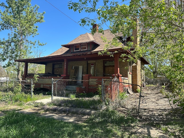 view of front of home featuring covered porch, brick siding, and a fenced front yard