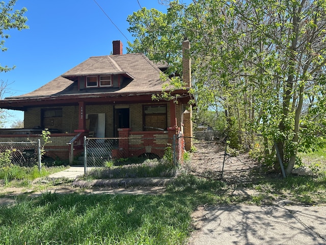 bungalow-style house featuring brick siding, covered porch, and a chimney