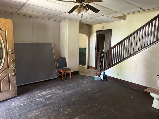 entryway featuring a drop ceiling, hardwood / wood-style flooring, a ceiling fan, baseboards, and arched walkways