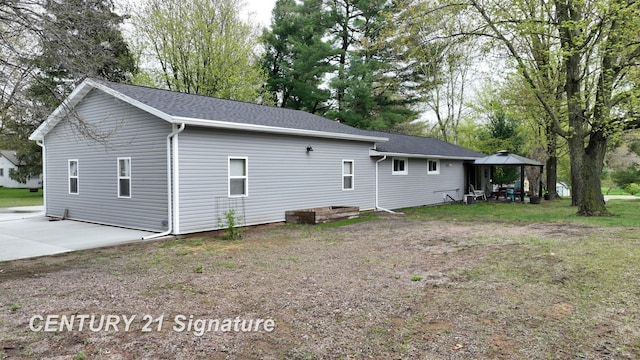 back of property featuring a gazebo and roof with shingles