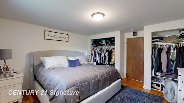 bedroom with two closets, wood finished floors, and baseboards