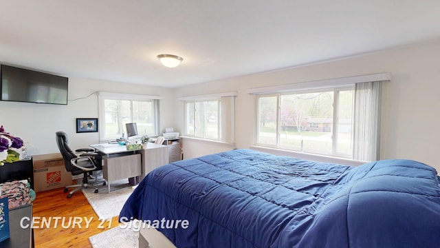 bedroom featuring light wood-style flooring and an office area